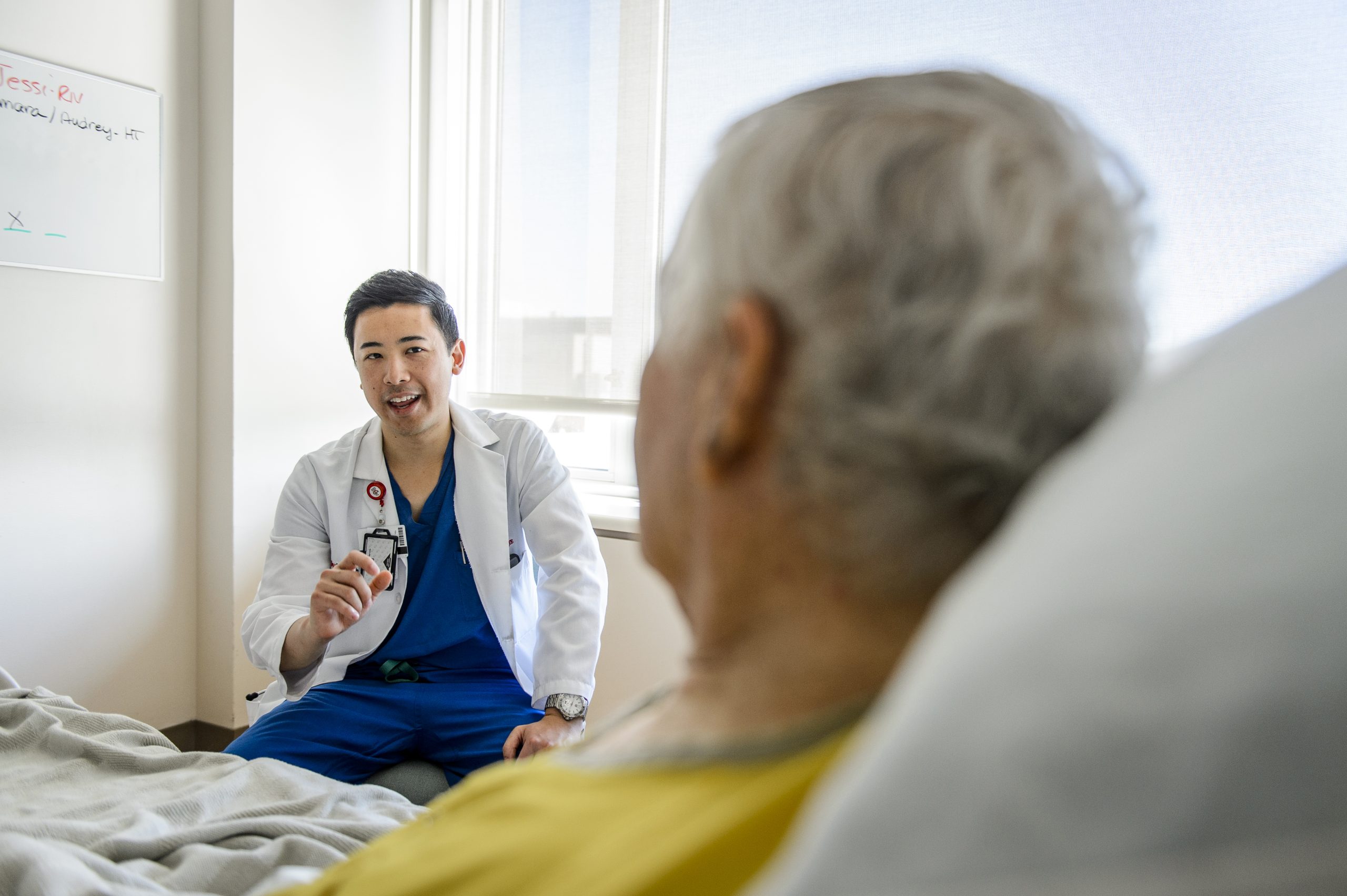 Doctor seated beside patient’s bed, engaging in conversation