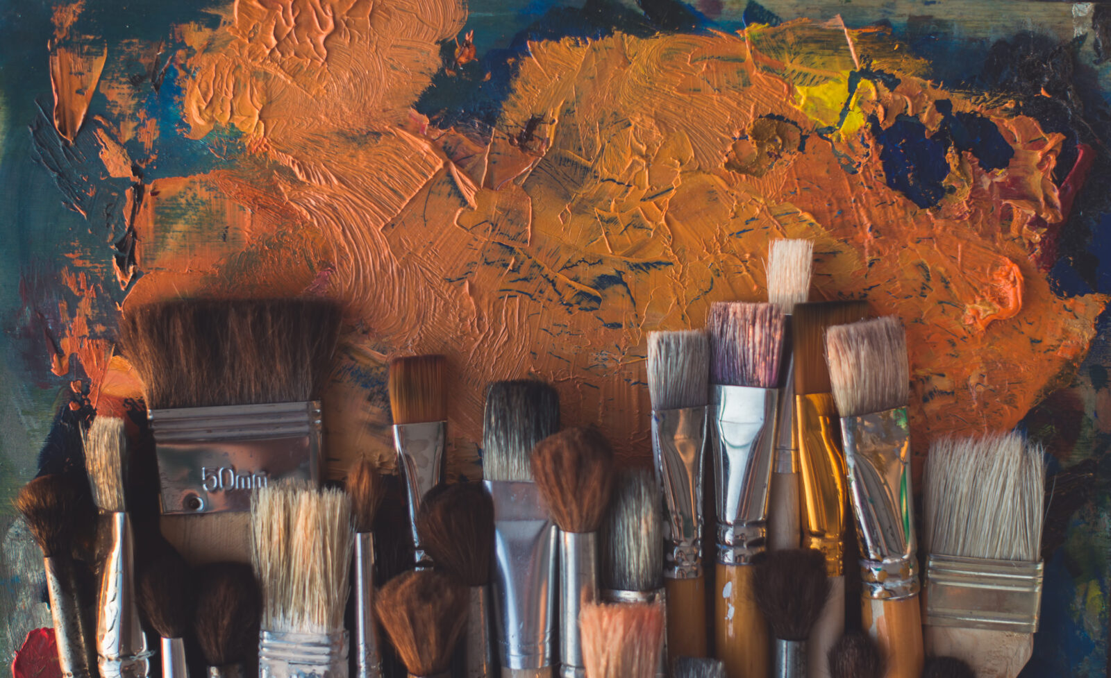 Top view picture of wooden paintbrush set different size with old palette on the background